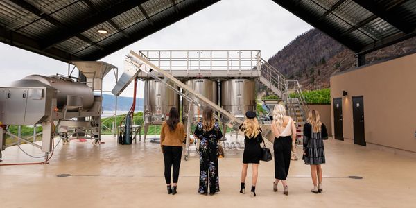 Group of women looking at large winery equipment