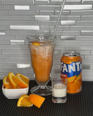 Glass of orange Fanta with ice and orange slices.