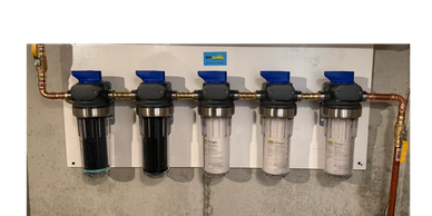 A row of water filtration units installed on a wall.
