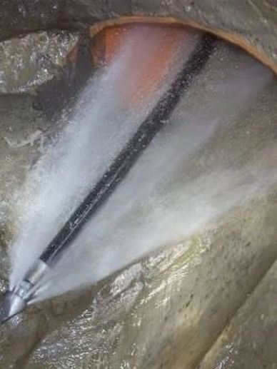 High-pressure water jet cleaning a pipe interior.