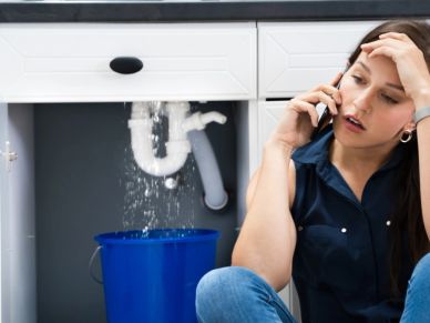 Woman on phone with leaking sink water.