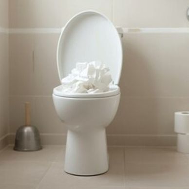 Overflowing toilet with tissue paper inside the bowl.