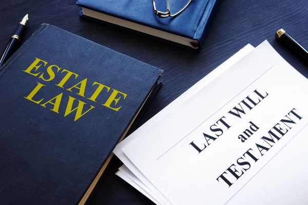 A book titled "ESTATE LAW" next to a "LAST WILL and TESTAMENT" document.
