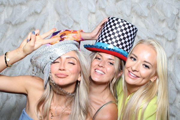 Three young woman smiling for Photo Booth photo, wearing photo booth props