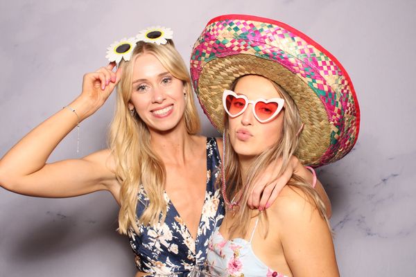 Two young women posing for photo, wearing Photo Booth props