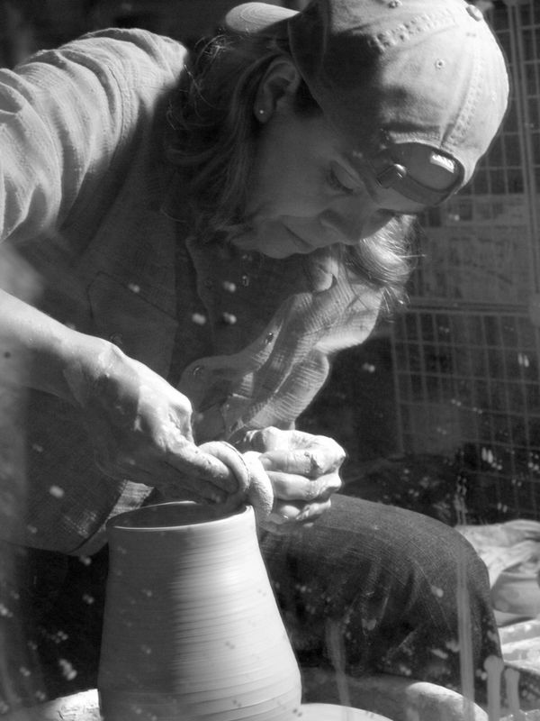 CL Ramsdell working in her clay studio. She is throwing a one of a kind vase on her wheel.