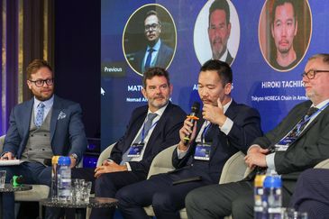 Panelists speaking at a conference or panel discussion.