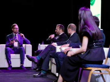 Panel discussion at a conference with four speakers.