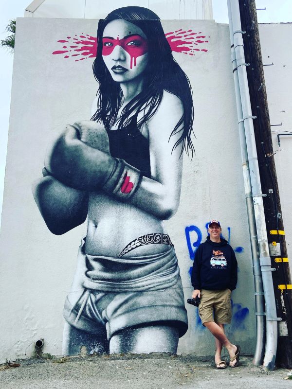 Street art of a female boxer with red eye mask and a man posing beside.