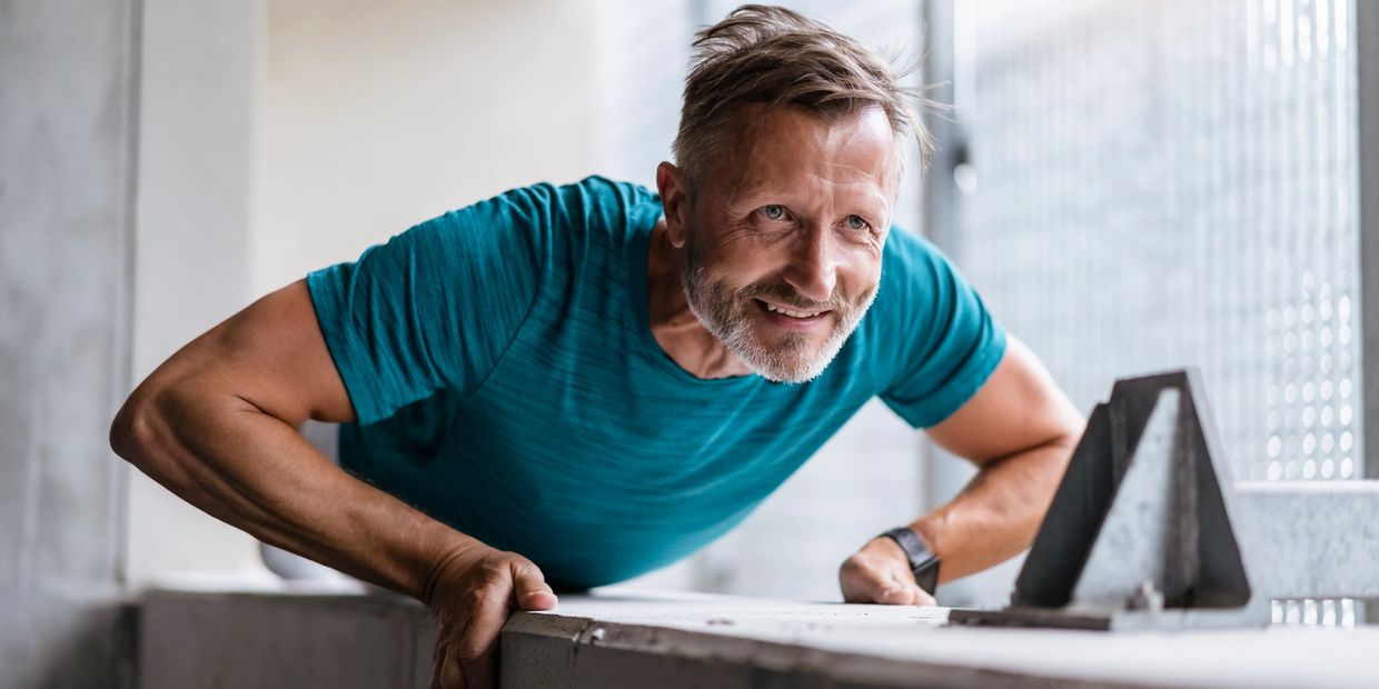 Man in teal shirt doing push-ups indoors with determination.