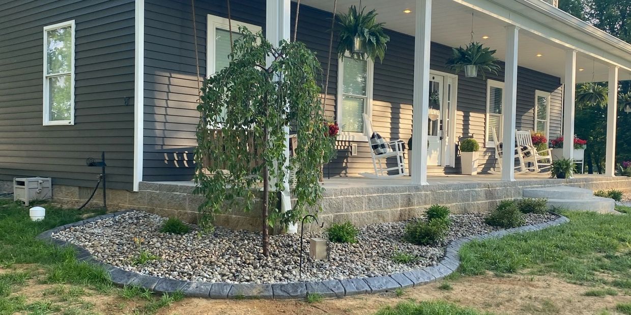 Landscaping around front porch with daylilies, azaleas, boxwoods and weeping cherry. 