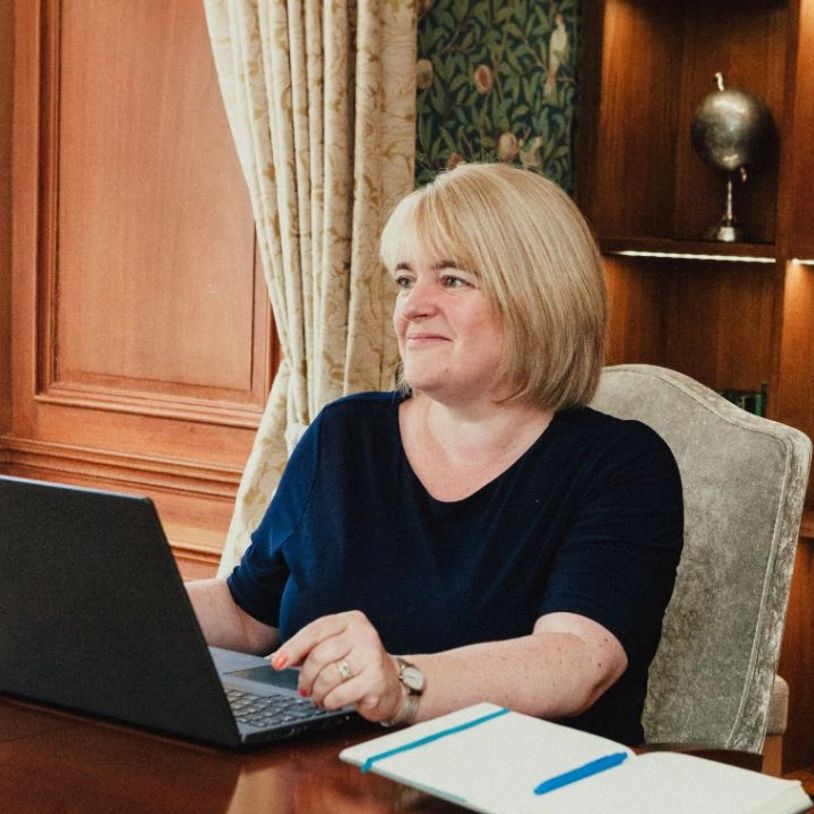 Woman working on a laptop in an elegant room.