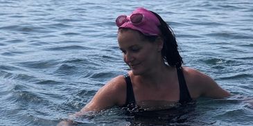 Woman swimming in a lake with a pink headband.