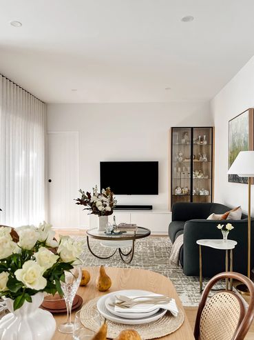 Modern living and dining area with linen curtains, oak table, curved lounge and green artwork