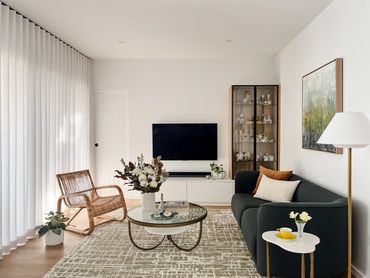 Modern living with linen curtains, oak table, curved lounge, textured rug and green artwork