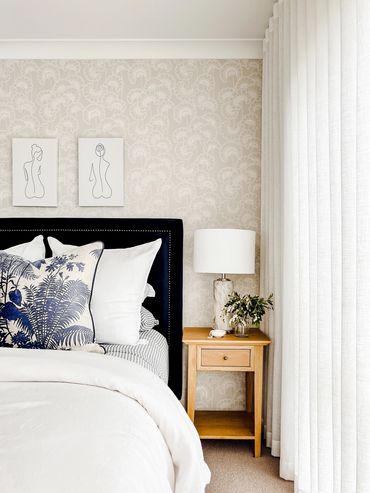 Light-filled Hamptons bedroom with linen curtains and bedding, oak, wallpaper & navy velvet bedhead.