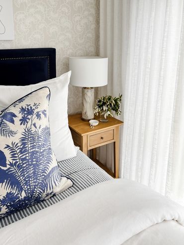 Light-filled Hamptons bedroom with linen curtains and bedding, oak, wallpaper & navy velvet bedhead.