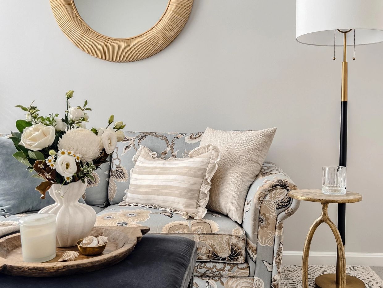 Cozy floral patterned sofa with decorative pillows and fresh flowers.