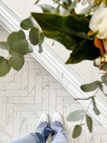Light-filled Hamptons bathroom with herringbone marble floor
