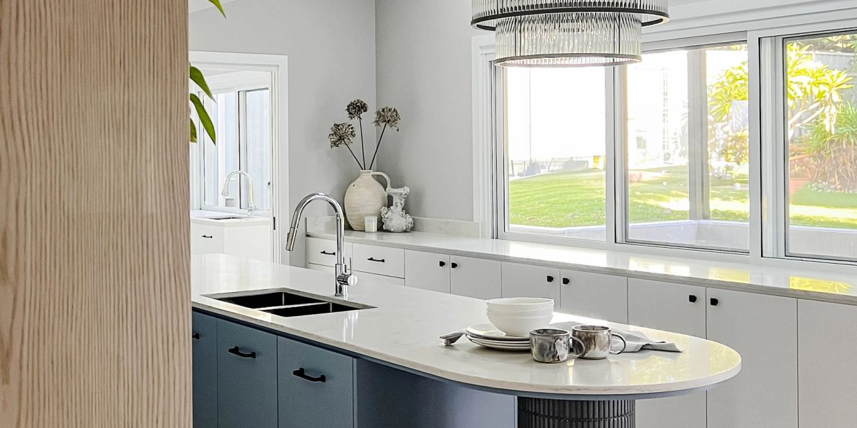 Modern kitchen island with sink and mugs on the countertop.