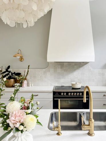 Coastal Kitchen with black range, light grey shaker cabinetry, concrete benchtop and chandelier.
