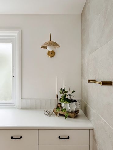 Light-filled, modern laundry with white cabinetry, black handles and rattan light.f