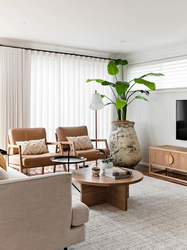 Mid-Century Modern lounge room with linen curtains, oak furniture and textured rug.