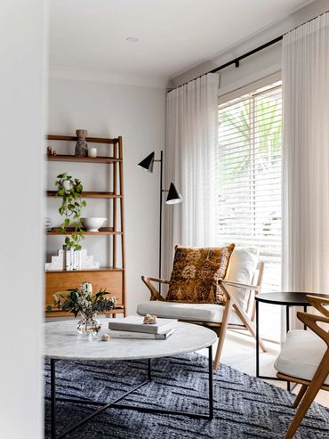 Mid-Century Modern lounge room with round marble coffee table, oak armchairs and textured rug.