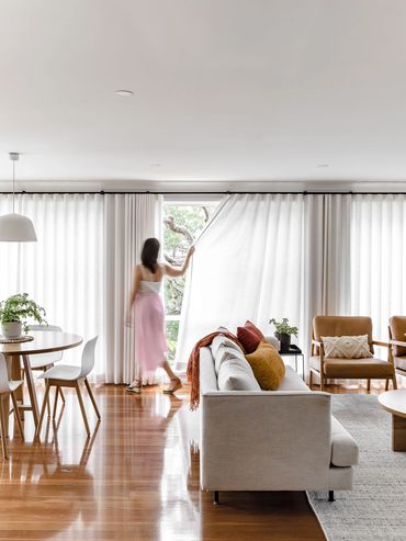 Mid-Century Modern lounge and dining room with linen curtains, oak furniture and textured rug.