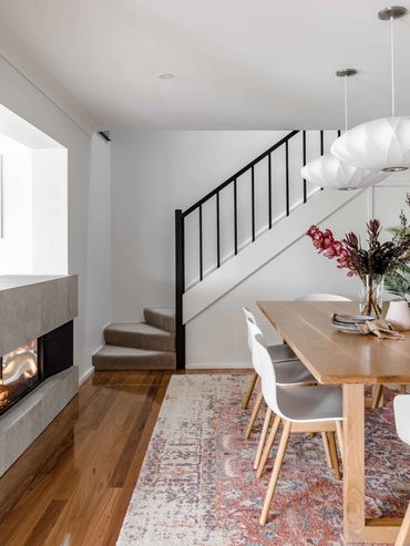 Mid-Century Modern Dining room with white pendant lights, oak table and textured rug.
