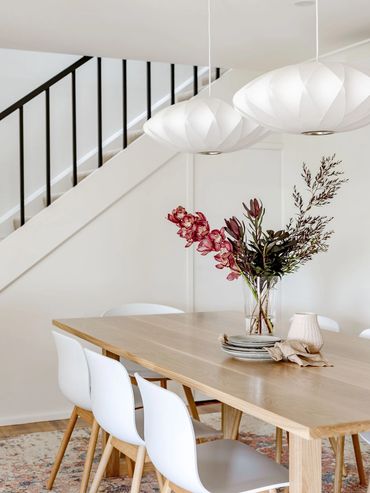 Mid-Century Modern Dining room with white pendant lights, oak table and textured rug.
