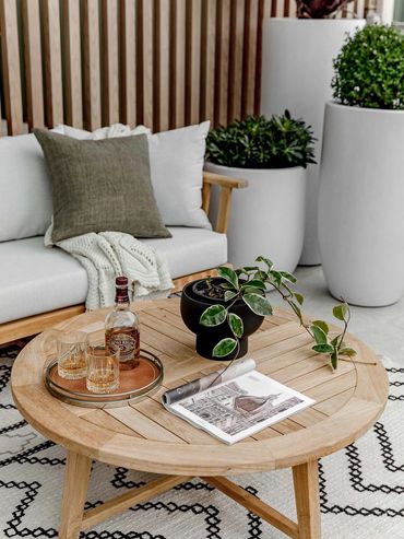 Outdoor lounge area with timber furniture, textured rug and timber feature wall.