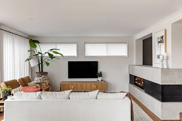 Mid-Century Modern lounge room with linen curtains, oak furniture, textured rug and custom fireplace