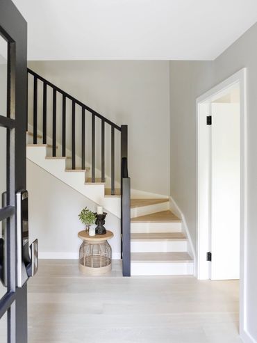 Hamtons entry with black timber handrail and oak staircase and oak floor. Light grey walls