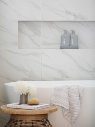 Light-filled marble bathroom with freestanding bath and neiche