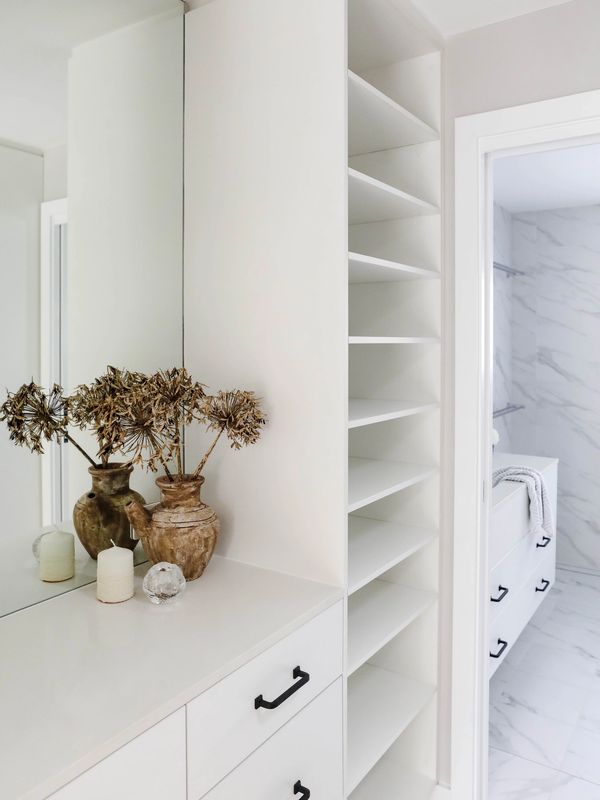 Custom wardrobe cabinetry with modern marble bathroom beyond