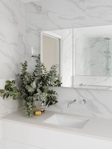 Light-filled marble bathroom with greenery.