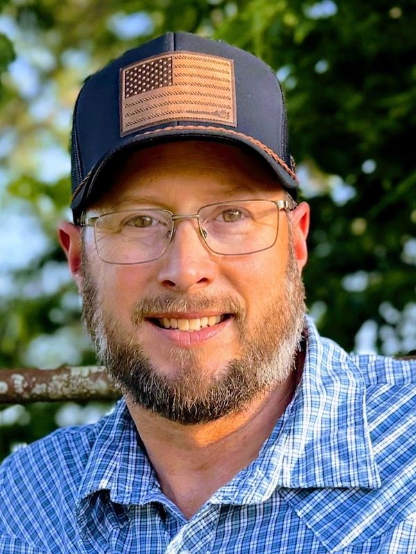 Smiling man with glasses and a cap.