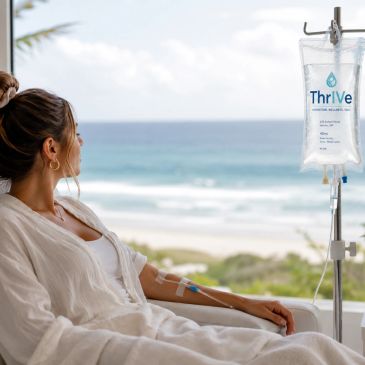 Woman receiving IV therapy while overlooking a beach view.