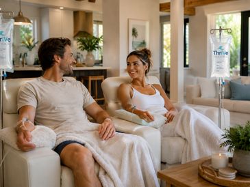 A couple relaxes in a cozy living room receiving IV therapy.