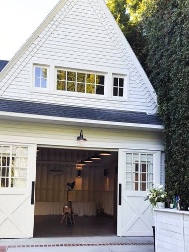 White barn-style building with open doors and interior lighting.
