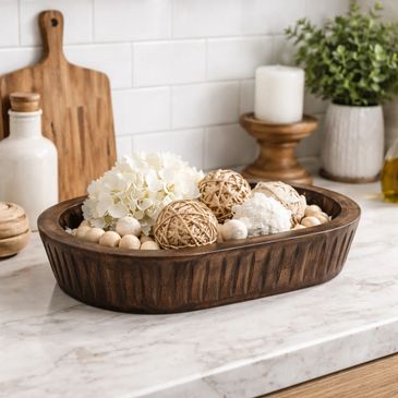 Decorative wooden bowl with natural elements on a kitchen countertop.