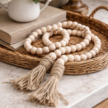 Decorative wooden bead garland with tassels on a woven tray.