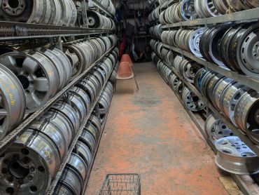 Aisle filled with car rims on shelves.