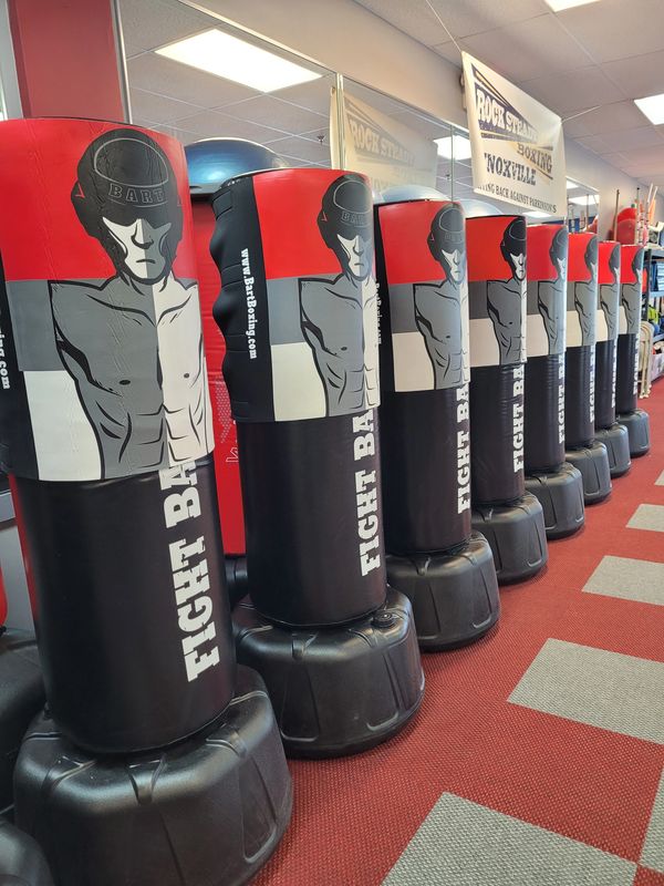 Row of Fight Bart punching bags in a boxing gym with red and gray carpet.