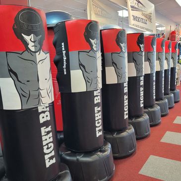Row of Fight Bart punching bags in a boxing gym with red and gray carpet.