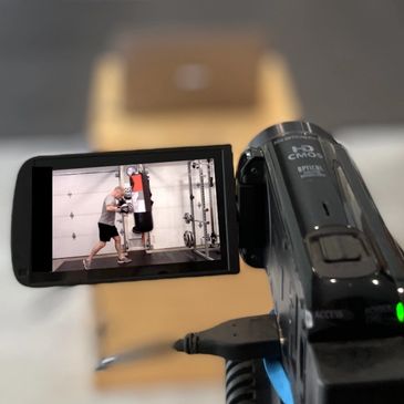 A camcorder screen shows a person boxing with a punching bag indoors.