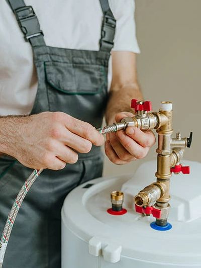 Plumber attaching hose to water heater valve.