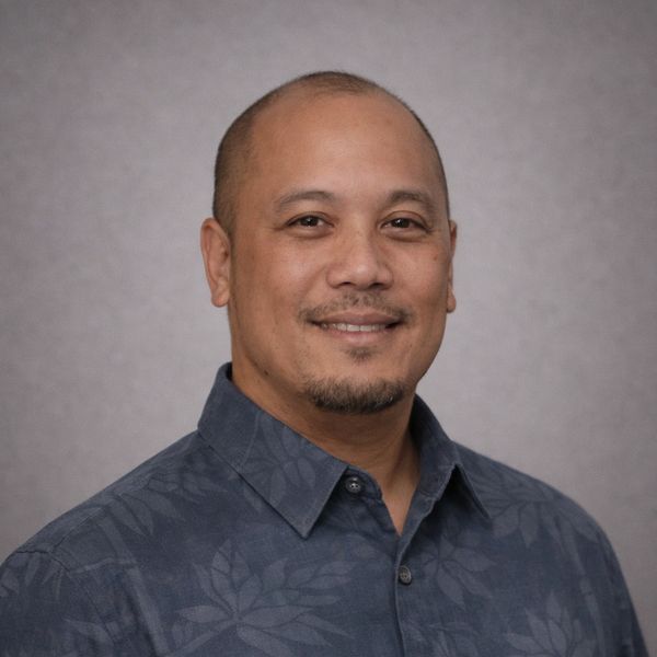 Smiling man in a patterned shirt.