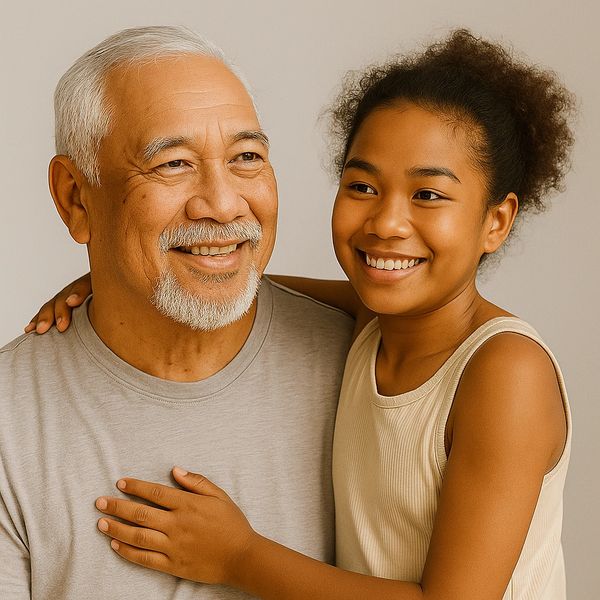 Smiling elderly man and young girl embracing warmly.
